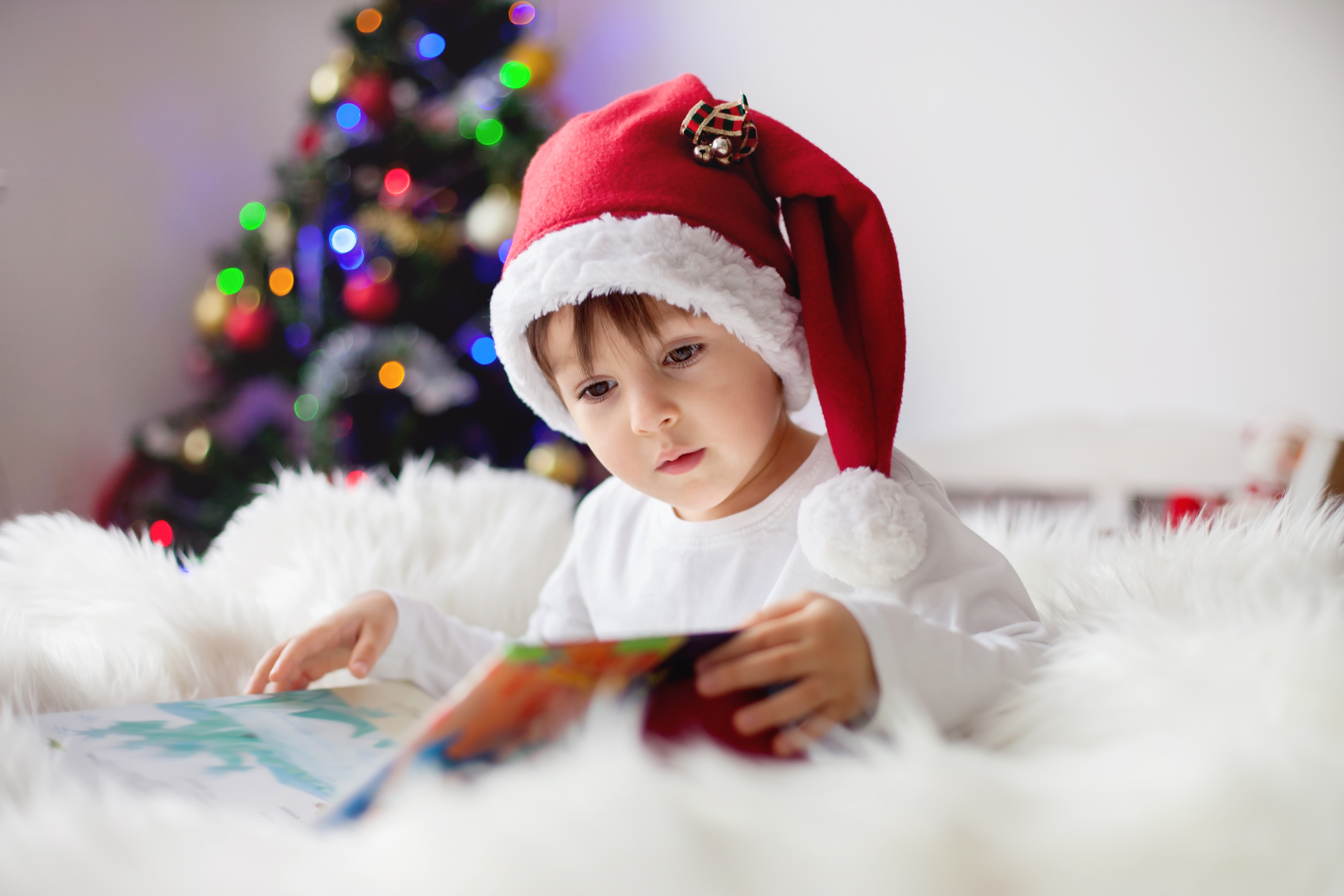 adorable-boy-reading-book-in-front-of-christmas-tree