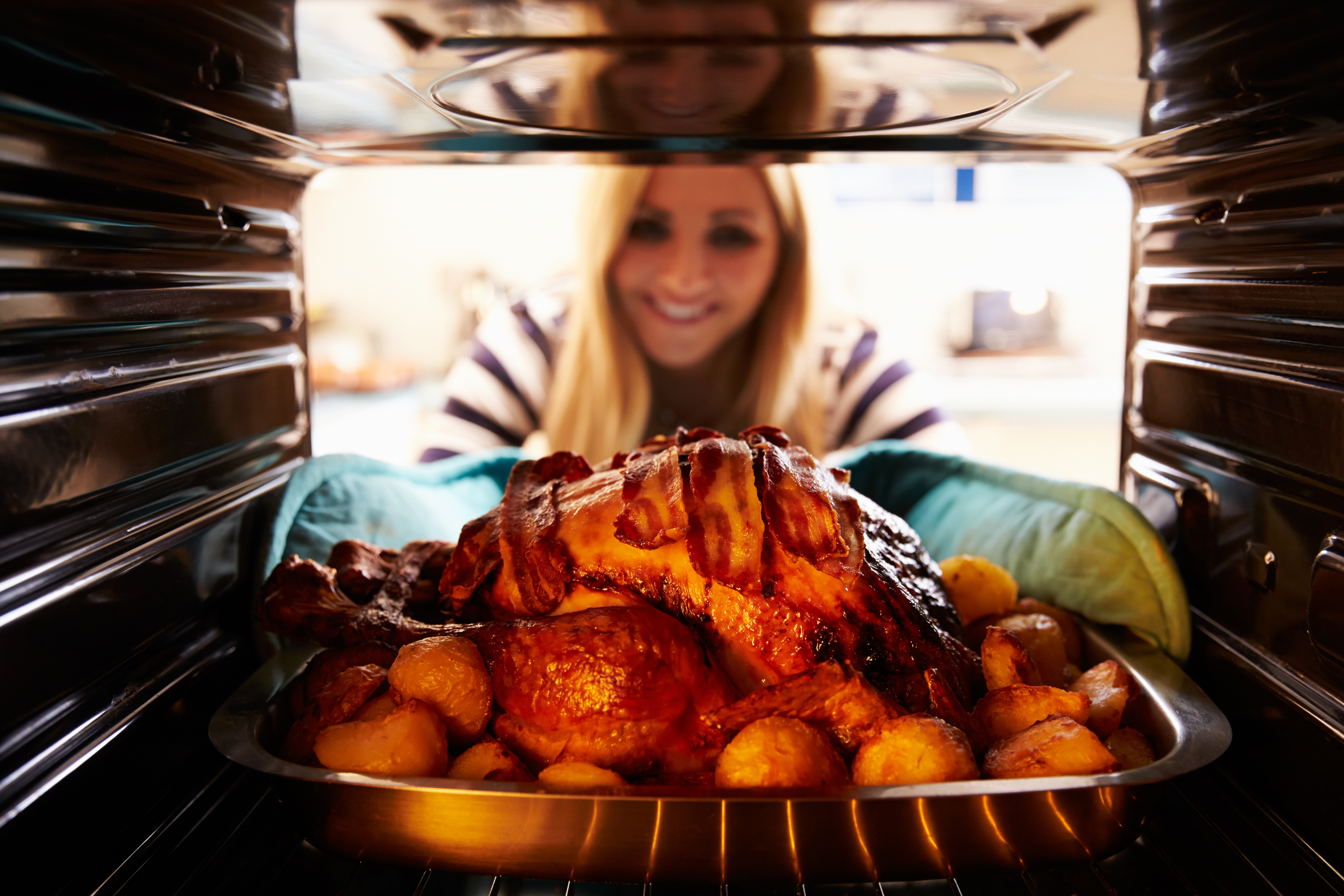 woman-taking-roast-turkey-out-of-oven